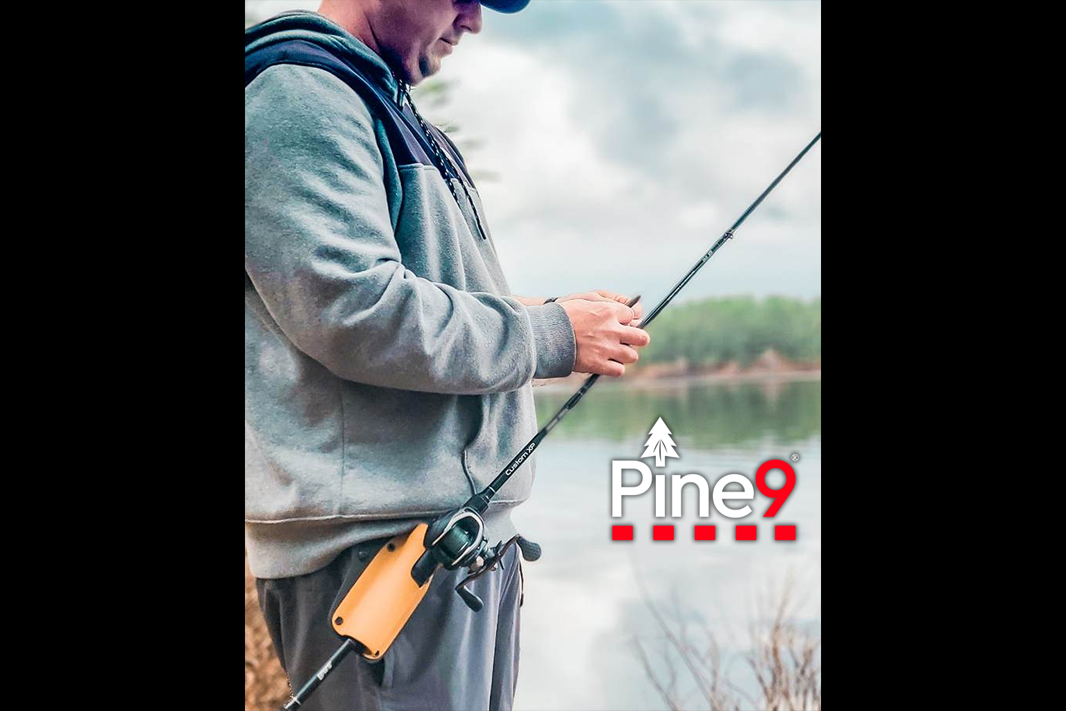 pine 9 JettyHawk fishing rod holster hands free hip rod hip holder man adjusting his fishing lure with his bait caster rod and reel are safely holstered while he uses both hands